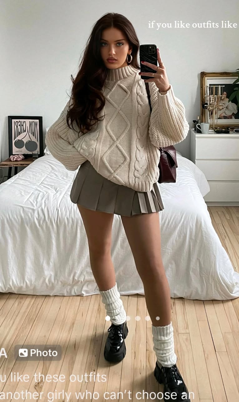 Pull oversize vert clair avec mini jupe noire et baskets blanches.